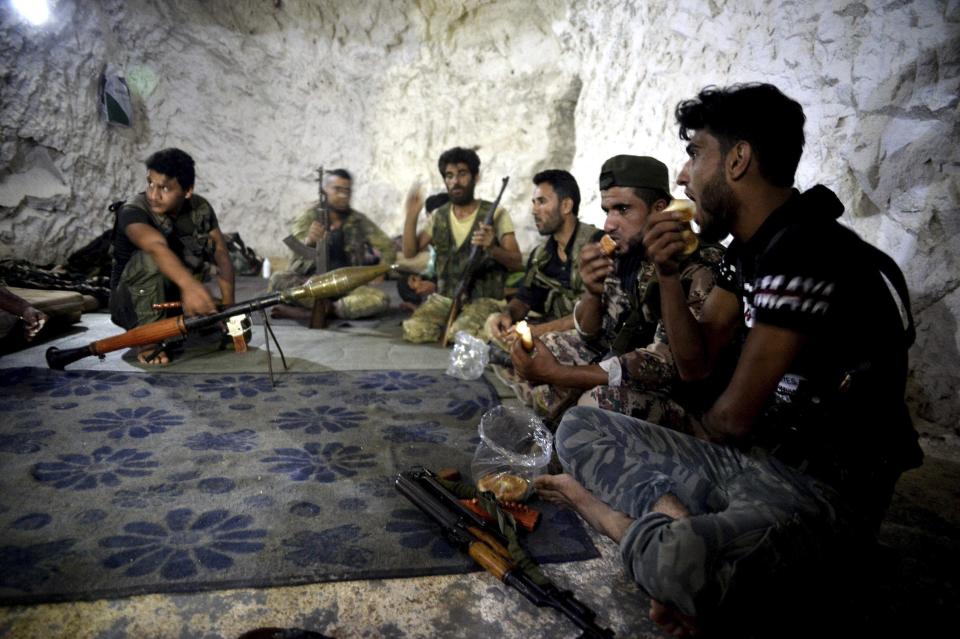 FILE - In this Sunday, Sept. 9, 2018 file photo, fighters with the Free Syrian army eat in a cave where they live, on the outskirts of the northern town of Jisr al-Shughur, Syria, west of the city of Idlib. Turkey's state-run Anadolu Agency news agency said Monday, Oct. 8, 2018, that Syrian rebels have finished withdrawing all their heavy weapons from the front lines in the northwestern province of Idlib. The move was part of a deal reached between Russia and Turkey to demilitarize the front lines between Syrian government forces and the opposition in and around the province. Idlib is the last major rebel stronghold in Syria. (Ugur Can/DHA via AP, File)