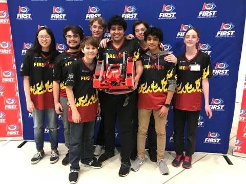 The South Bend area-based Fire Wires robotics team poses with its traffic cone-stacking robot.