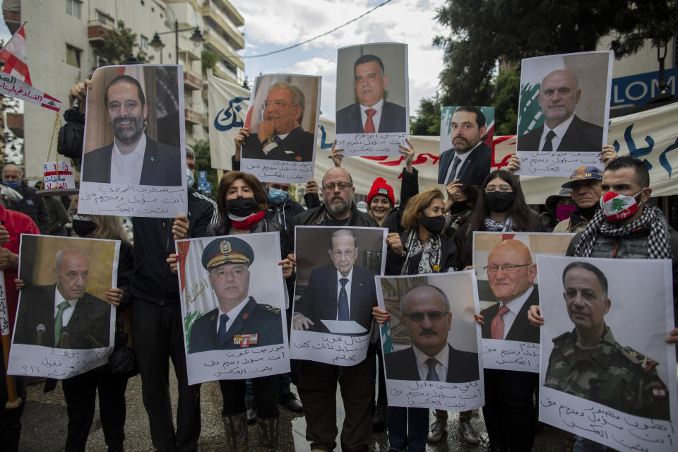 FILE - Anti-government protesters hold pictures of Lebanese leaders during a protest outside the house of Judge Fadi Sawwan, the lead judicial investigator into the catastrophic blast at Beirut's port in the deadly August blast, in Beirut, Lebanon, Nov. 26, 2020. It has been two years since a warehouse full of ammonium nitrate at Beirut's port exploded, destroying large parts of the city, killing more than 215 people and injuring thousands. In 2022 many families are losing hope of ever finding justice. (AP Photo/Hassan Ammar, File)