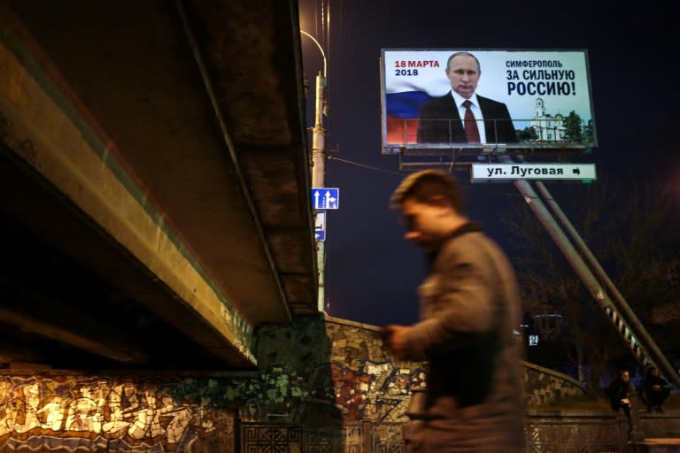 A man walks past a campaign billboard of Russian President Vladimir Putin, reading "Simferopol for a Strong Russia!" in Simferopol, Crimea, on March 15, 2018. Russia will vote for President on March 18, 2018