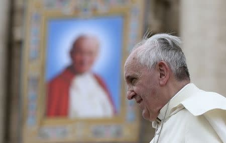 Pope Francis passes next to a tapestry of the late Pope John Paul II, as he leaves at the end of his weekly general audience at St. Peter's Square at the Vatican April 30, 2014. REUTERS/Alessandro Bianchi