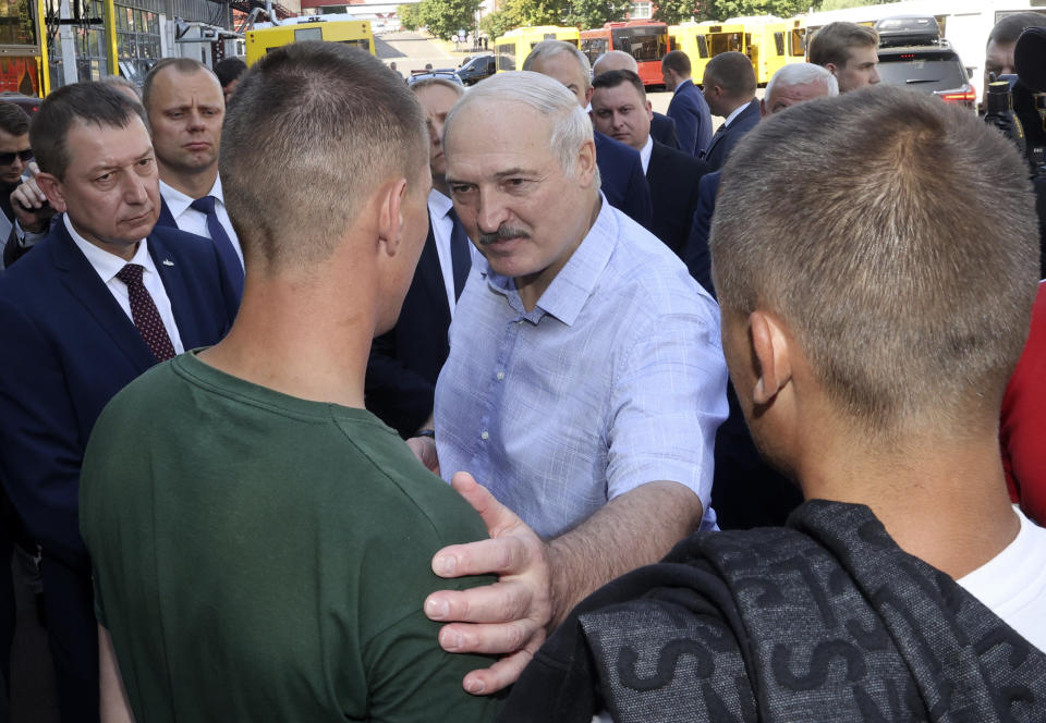 Belarusian President Alexander Lukashenko, center, speaks to an employee of the Minsk Wheel Tractor Plant in Minsk, Belarus, Monday, Aug. 17, 2020. Workers heckled President Alexander Lukashenko as he visited a factory and strikes grew across Belarus, raising the pressure on the authoritarian leader to step down after 26 years in office. (Nikolai Petrov/BelTA Pool Photo via AP)