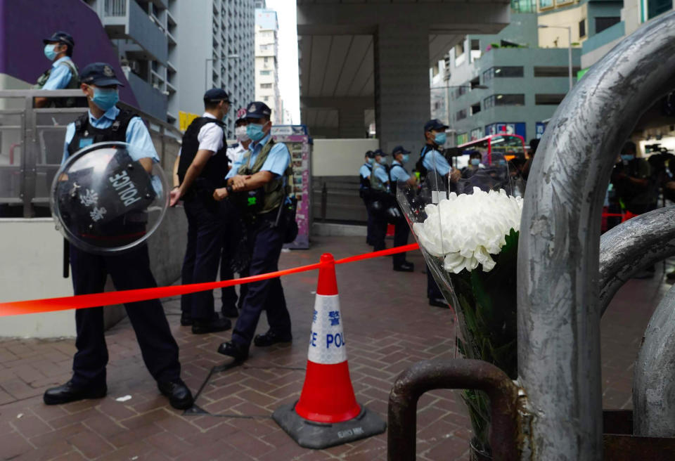 White flowers are placed against police officers outside the Prince Edward subway station in Hong Kong Monday, Aug. 31, 2020. Aug. 31 is the first anniversary of police raid on Prince Edward subway station which resulted in widespread images of police beating people and drenching them with pepper spray in subway carriages. (AP Photo/Vincent Yu)