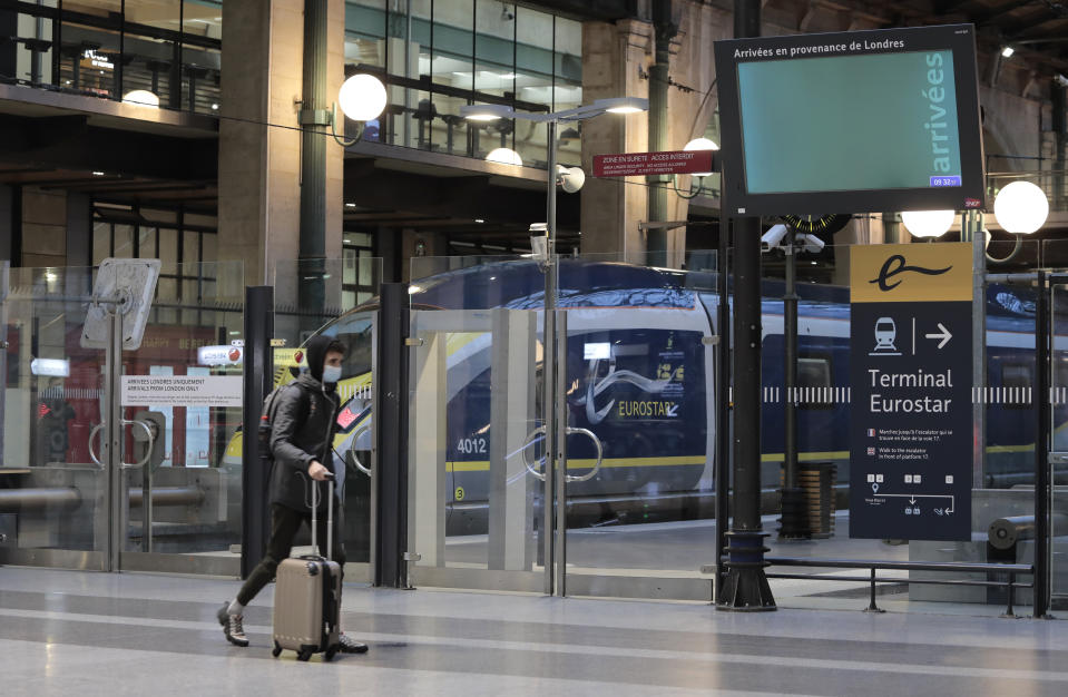 A man wearing a face mask pulls a suitcase past a Eurostar train at Gare du Nord train station in Paris, Monday Dec. 21, 2020. France is banning all travel from the U.K. for 48 hours in an attempt to make sure that a new strain of the coronavirus in Britain doesn't reach its shores. (AP Photo/Lewis Joly)