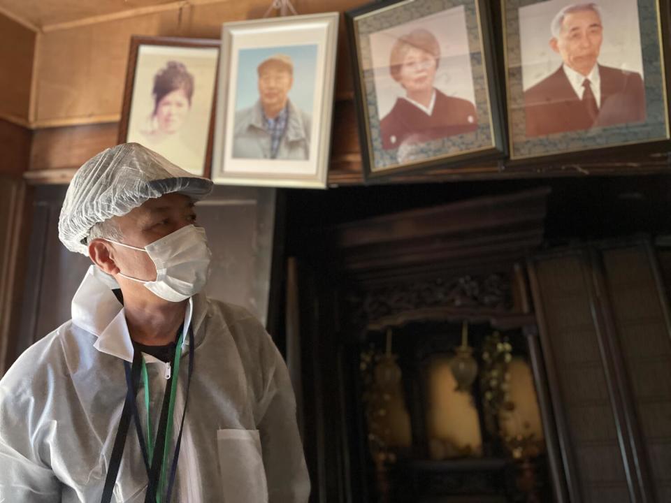 Man in a mask beneath four framed photographic portraits