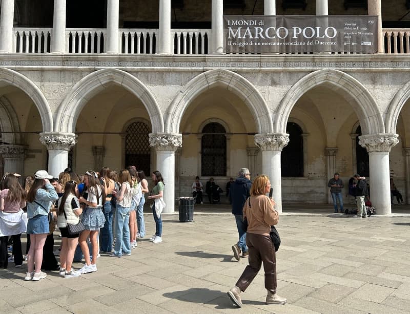 Tourists stand in front of the Doge's Palace, where an exhibition on the Asian traveller Marco Polo (presumably 1254-1924) has opened. Venice is commemorating the 700th anniversary of the death of its most famous citizen with this major exhibition. Christoph Sator/dpa