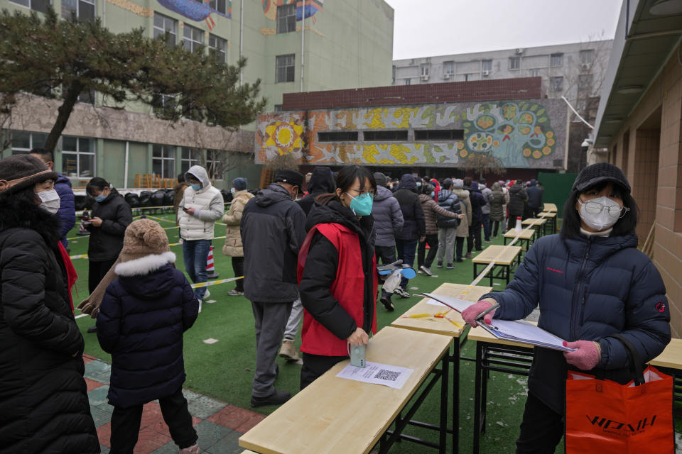 Volunteers wearing face masks to help protect from the coronavirus check name lists at a coronavirus testing facility at a school in Fengtai District in Beijing, Monday, Jan. 24, 2022. Chinese authorities have lifted a monthlong lockdown of Xi'an and its 13 million residents as infections subside ahead of the Winter Olympics. Meanwhile, the 2 million residents of one Beijing district are being tested following a series of cases in the capital. (AP Photo/Andy Wong)