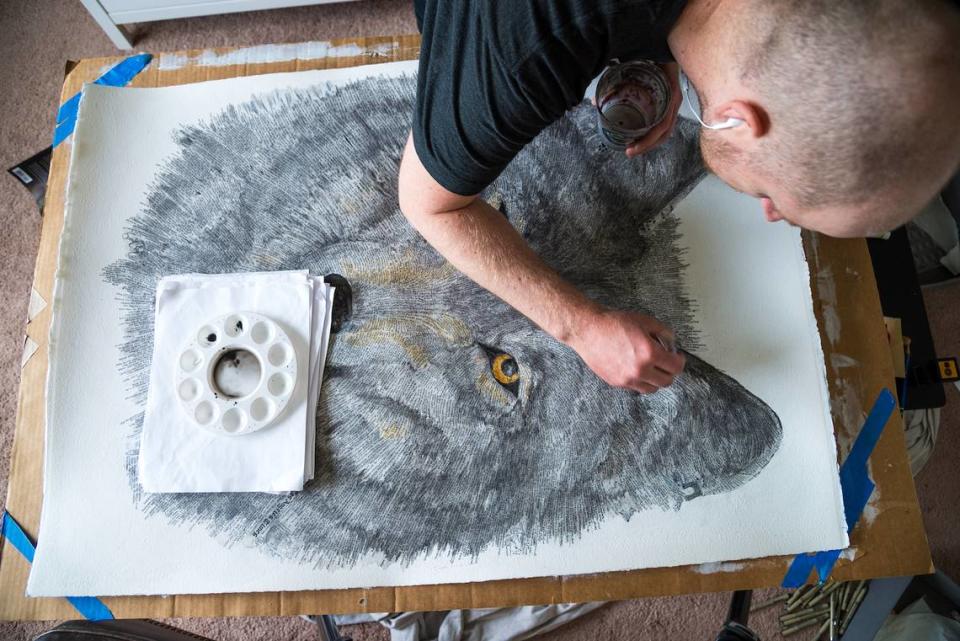 Erik Fremstad works on “Canis Lupus,” now on view at Lakewold Gardens. The image is made up largely of words, information about the species and the way it has been threatened by humans.