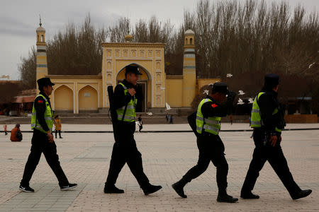 FILE PHOTO: A police patrol walk in front of the Id Kah Mosque in the old city of Kashgar, Xinjiang Uighur Autonomous Region, China, March 22, 2017. REUTERS/Thomas Peter