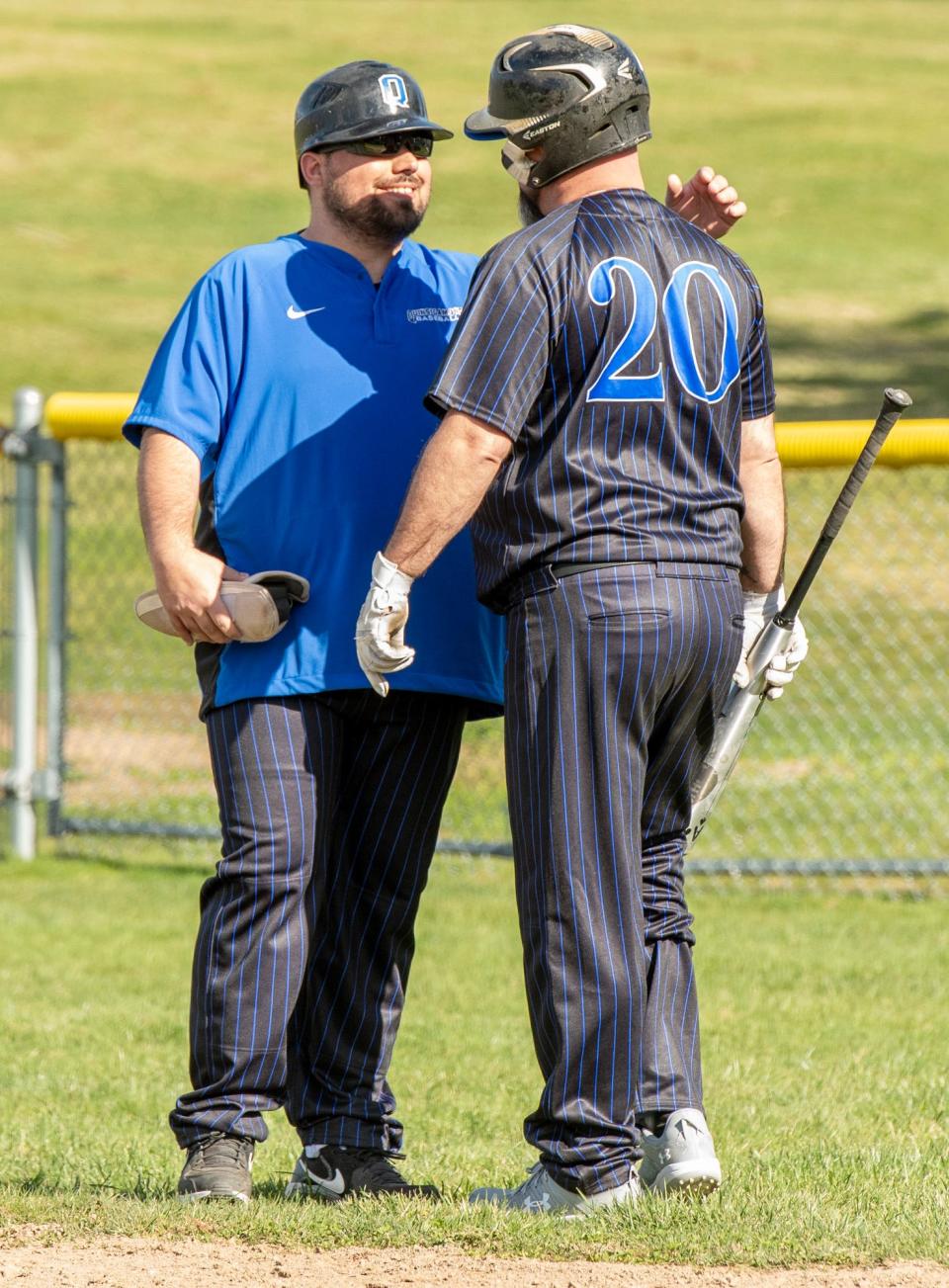 Quinsigamond's Paul Landry chats with first-base coach Kyle Paganelli before his pinch hit at bat Tuesday.