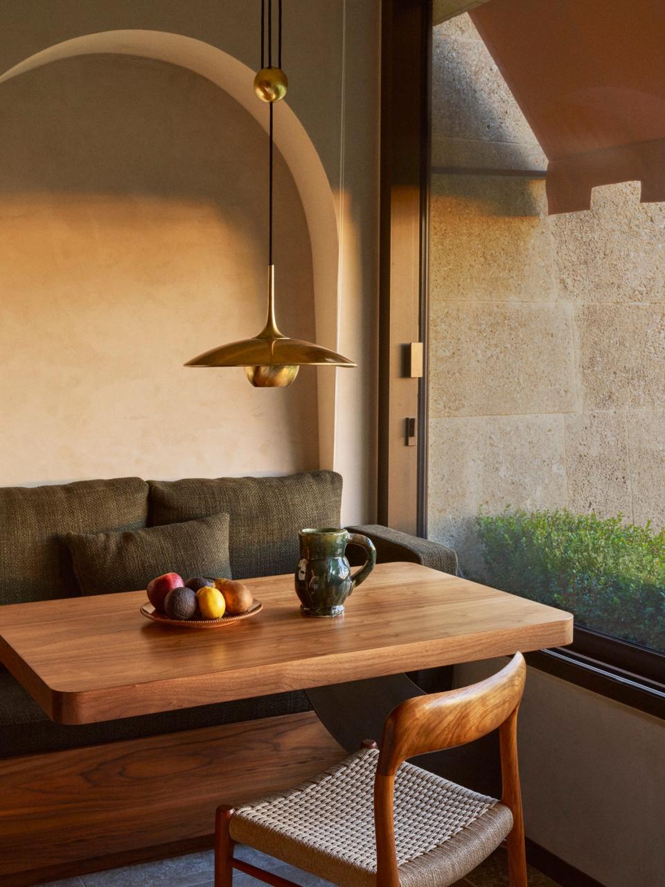 In the kitchen dining area, the adjustable counterweight gold pendant lamp by Florian Schulz pairs nicely with a bench seat.