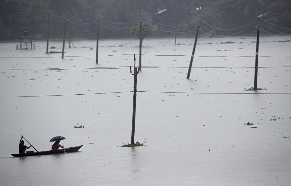 Villagers cross floodwaters in a small boat in the Morigaon district of Assam, India, Friday, June 26, 2020. Following incessant rainfall, the Brahmaputra River and its tributaries continued to flood several districts in the state. (AP Photo/Anupam Nath)