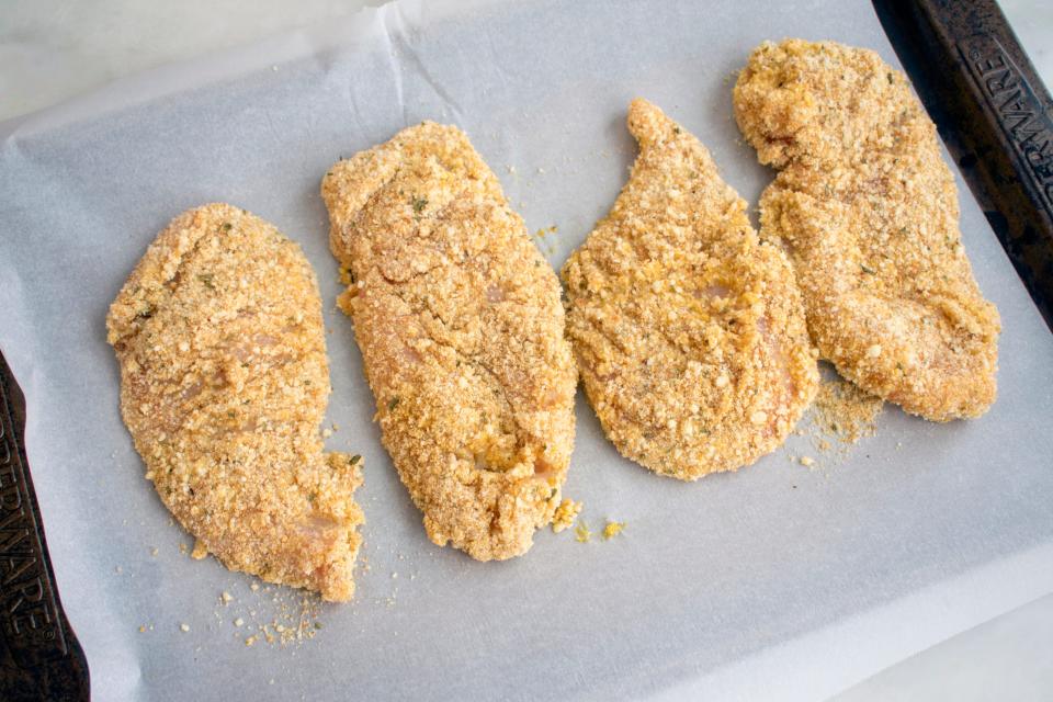 breaded chicken breasts on a piece of parchment paper