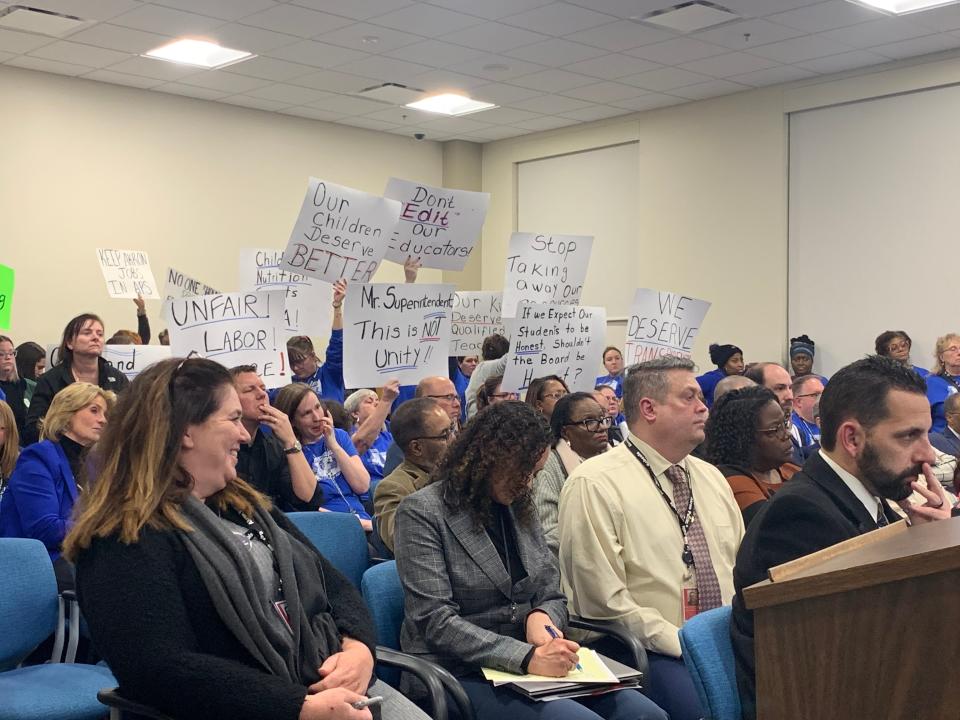 Akron Education Association union members hold signs in opposition to the Varsity Tutors contract at the Monday Akron Public Schools Board of Education meeting.