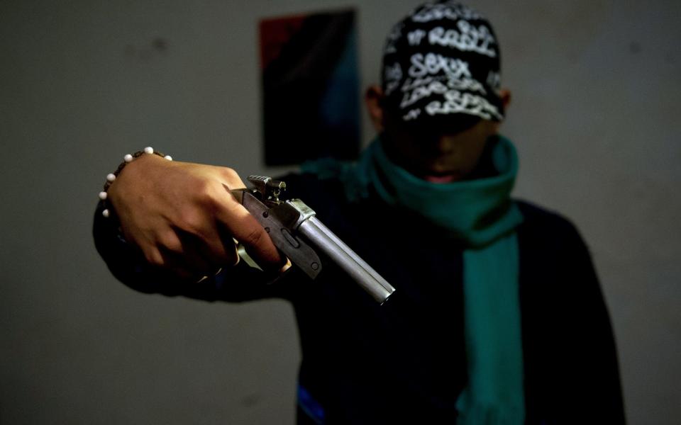 A gang member poses with a homemade gun at the Siloe neighborhood in Cali, Colombia
