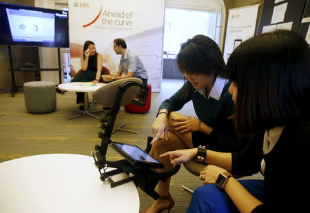 UBS employees demonstrate how their eye movements are being tracked to provide feedback on the interface design of a banking application on a tablet computer at their innovation center Evolve in Singapore March 17, 2016. REUTERS/Edgar Su