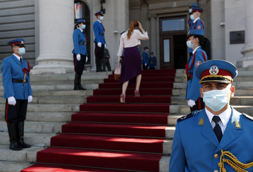 Serbia's army guard of honor wearing face masks to prevent the spread of coronavirus, stand in front of the parliament building before the inaugural parliament session in Belgrade, Serbia, Monday, Aug. 3, 2020. The Serbian parliament reconvened Monday amid protests by opposition and far-right supporters who claim the parliamentary election that was overwhelmingly won by the ruling populists was rigged. (AP Photo/Darko Vojinovic)