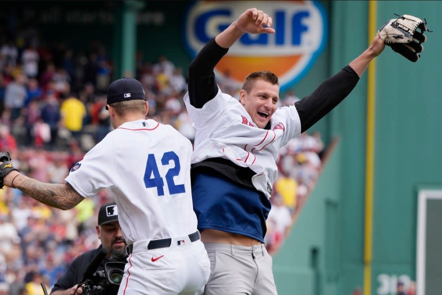 Former New England Patriots NFL football player Rob Gronkowski, right, reacts with Boston Red Sox’s <a class="link " href="https://sports.yahoo.com/mlb/players/10852/" data-i13n="sec:content-canvas;subsec:anchor_text;elm:context_link" data-ylk="slk:Tanner Houck;sec:content-canvas;subsec:anchor_text;elm:context_link;itc:0">Tanner Houck</a>, left, after spiking the ball instead of throwing it during the ceremonial first pitch before a baseball game against the Cleveland Guardians, Monday, April 15, 2024, in Boston. (AP Photo/Michael Dwyer)