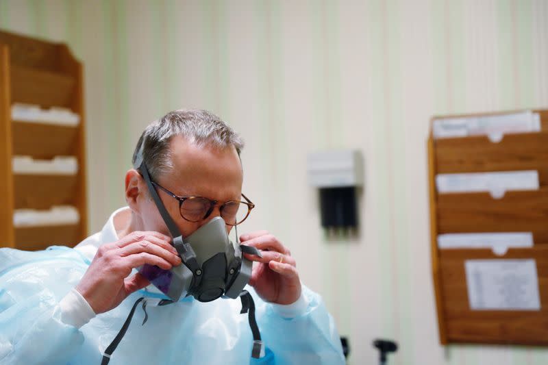 Dr Greg Gulbransen dons personal protective gear to see a patient that has tested positive for the coronavirus disease (COVID-19) at his pediatric practice in Oyster Bay, New York