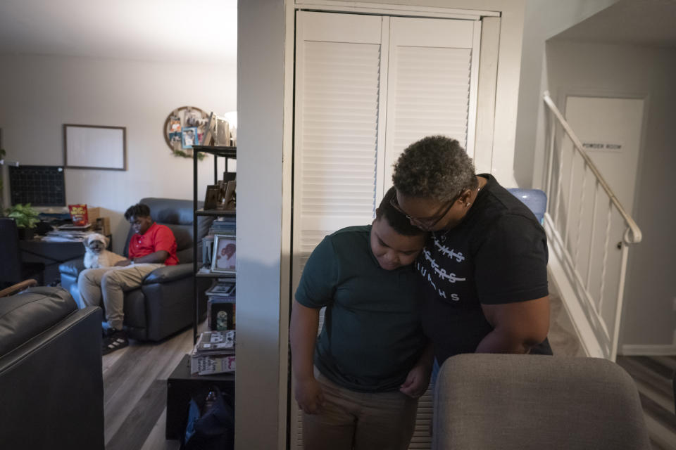 Melanese Marr-Thomas hugs her youngest child, Savion Thomas, while her other son, Zachary Marr, shares a seat with their pet dog, Ryder, in their living room in District Heights, Md., on Wednesday, Sept. 21, 2022. (AP Photo/Wong Maye-E)