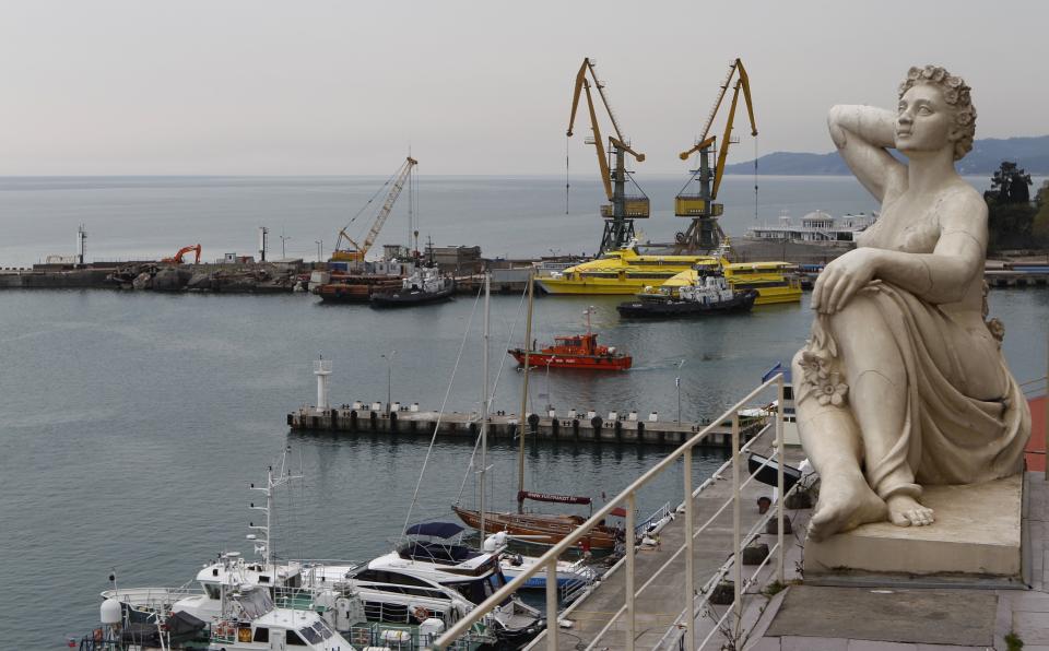 FILE - In this May 19, 2011, file photo, an old Soviet style statue, right, is display over the sea port in the Black Sea resort of Sochi, southern Russia. For visitors to the Winter Olympics, Sochi may feel like a landscape from a dream. Palm trees evoke a tropical seaside resort, but the Black Sea itself is seriously cold; turn away from the palms and the jagged, snow-covered peaks of the Caucasus Mountains rise nearby. (AP Photo/Alexander Zemlianichenko, File )