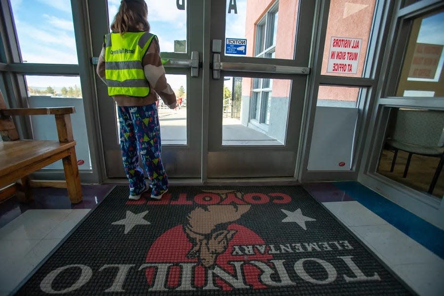 A member of the “Coyote Hall Patrol” waits to welcome arriving students to Tornillo ISD’s PreK-8th campus, Monday, Feb. 26. Staff member Cassandra Soto founded the successful Hall Patrol program as an incentive for students with high numbers of absences and tardies to arrive early.