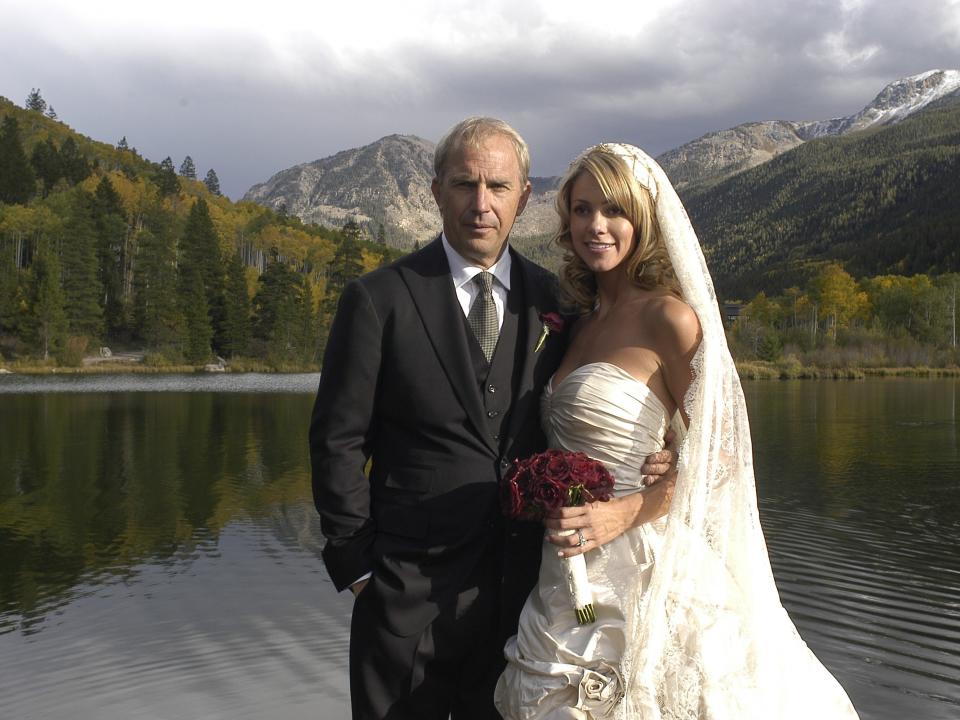 The bride and groom posing for a photo against the backdrop of a lake and mountains.