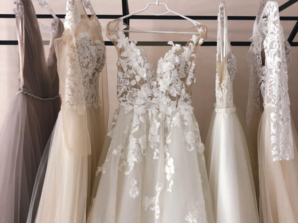 An assortment of wedding dresses hang on a rack.