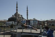 Backdropped by the historical Yeni Cami (New Mosque), a youth jumps from the Galata Bridge into the Golden Horn leading to the Bosphorus Strait separating Europe and Asia, in Istanbul, Friday, May 14, 2021.Turkey is in the final days of a full coronavirus lockdown and the government has ordered people to stay home and businesses to close amid a huge surge in new daily infections. But millions of workers are exempt and so are foreign tourists. Turkey is courting international tourists during an economic downturn and needs the foreign currencies that tourism brings to help the economy as the Turkish lira continues to sink. (AP Photo/Emrah Gurel)