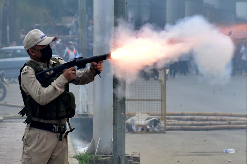 A police officer fires a tear smoke shell to disperse demonstrators during a protest march, in Imphal