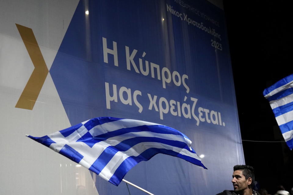 A flag seller waves a Greek flag outside the headquarter of presidential candidate Nikos Christodoulides, in Nicosia, Cyprus, Sunday, Feb. 12, 2023. Former foreign minister Nikos Christodoulides has been elected as the new president of Cyprus in a runoff election. (AP Photo/Petros Karadjias)