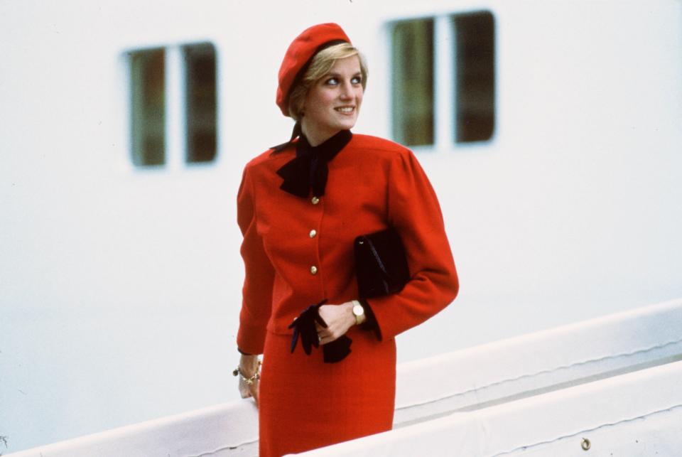 <p> What does one wear to an event where a ship is being named after you? Wearing a charm bracelet, of course! This red skirt suit and matching beret with black trim and matching black accessories is considered pretty quintessentially Princess Diana fashion: conservative and appropriate for a formal royal event, but with some flair, individuality, and fun. This photo, of her looking up at the "Royal Princess," is one of her most well-known images. </p>