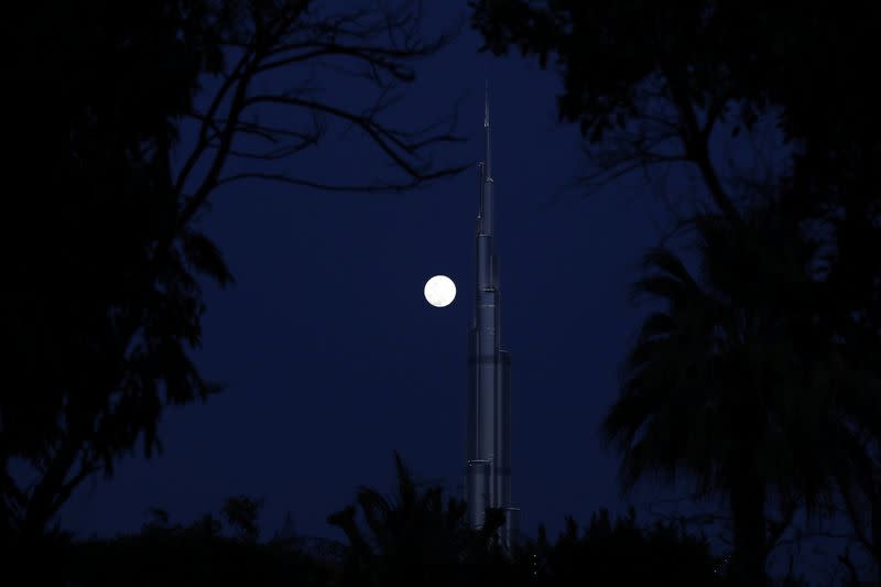 A waxing gibbous moon rises behind the Burj Khalifa, the world's tallest building, ahead of the 'Super Pink Moon', in Dubai