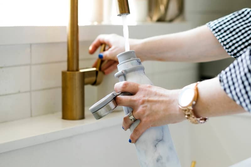 Woman filling up a reusable water bottle at the sink
