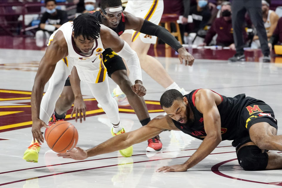 Minnesota's Marcus Carr, left, and Maryland's Donta Scott, right, reach for a loose ball in the first half of an NCAA college basketball game, Saturday, Jan. 23, 2021, in Minneapolis. (AP Photo/Jim Mone)