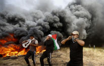 <p>Palestinian protesters chant slogans next to burning tires during clashes with Israeli troops along Gaza’s border with Israel, east of Khan Younis, Gaza Strip, Friday, April 6, 2018. (Photo: Adel Hana/AP) </p>