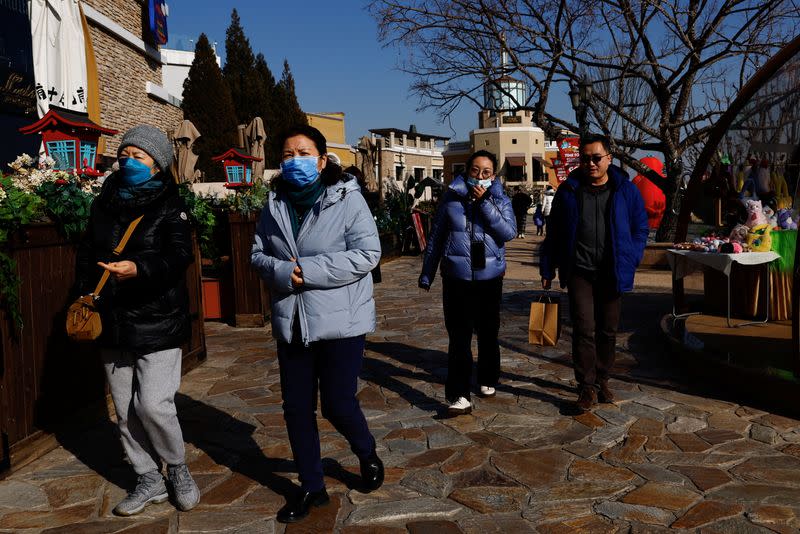 People walk past restaurant in a shopping area in Beijing