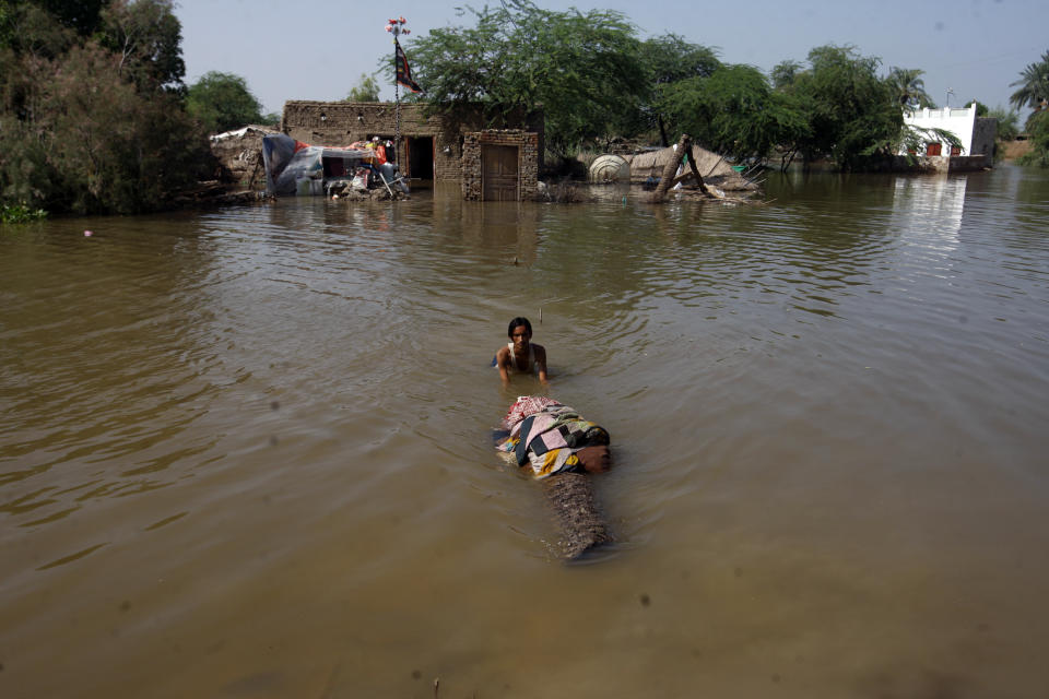 A man carries salvageable belongings from his flood-hit home in Shikarpur district of Sindh province, of Pakistan, Wednesday, Aug. 31, 2022. Officials in Pakistan raised concerns Wednesday over the spread of waterborne diseases among thousands of flood victims as flood waters from powerful monsoon rains began to recede in many parts of the country. (AP Photo/Fareed Khan)