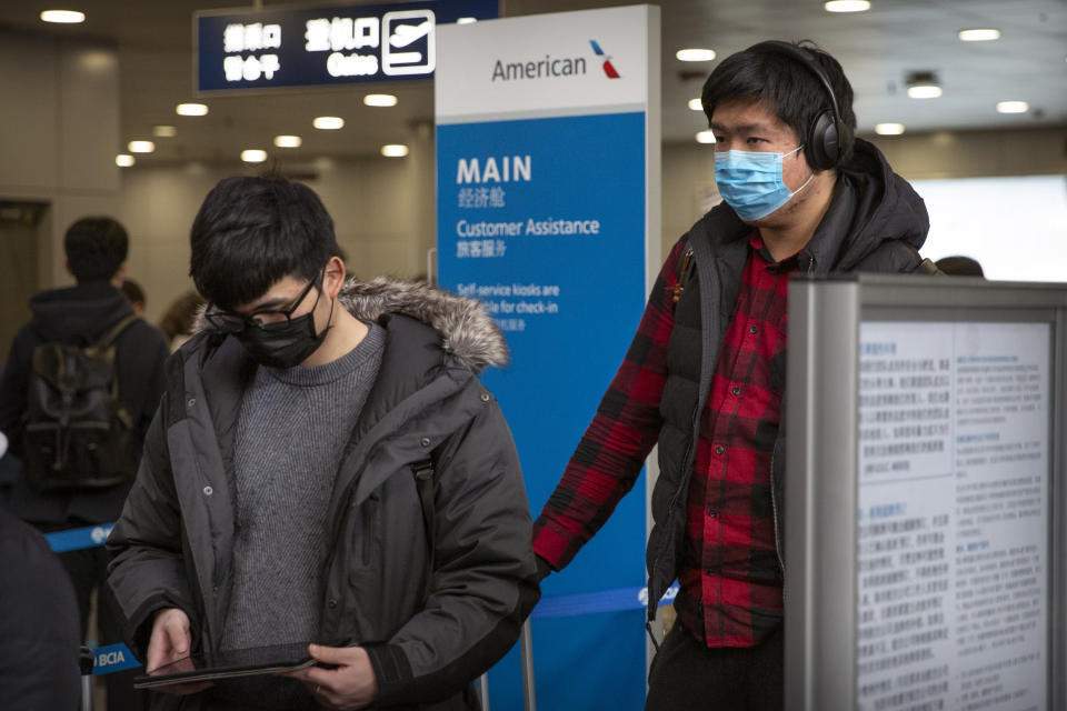 Travelers wearing face masks line up to check in for an American Airlines flight to Los Angeles at Beijing Capital International Airport in Beijing, Thursday, Jan. 30, 2020. China counted 170 deaths from a new virus Thursday and more countries reported infections, including some spread locally, as foreign evacuees from China's worst-hit region returned home to medical observation and even isolation. (AP Photo/Mark Schiefelbein)