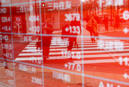 FILE PHOTO - Pedestrians are reflected on an electronic board showing stock prices outside a brokerage in Tokyo, Japan December 27, 2018. REUTERS/Kim Kyung-Hoon