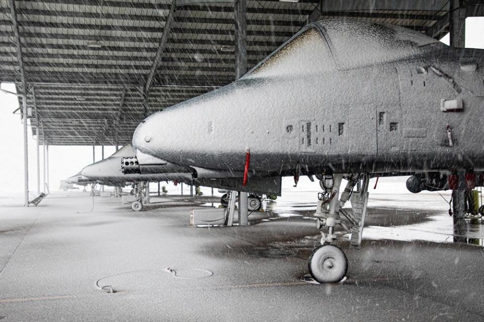 A line of aircraft covered in snow