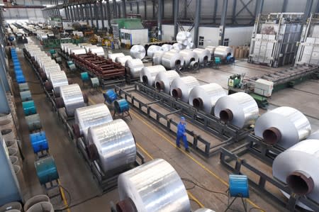 Workers are seen next to aluminium rolls at a plant in Binzhou