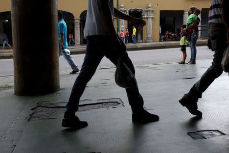 Norymar Torres (R), holds the hand of her son Lorenzo, 5, and carries her son Leonardo, 6, who is a neurological patient being treated with anticonvulsants, while they wait for transportation on the street in Caracas, Venezuela January 24, 2017. REUTERS/Carlos Garcia Rawlins