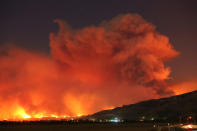 <p>Smoke rises into the night sky as strong winds push the Thomas Fire across thousands of acres near Santa Paula, Calif., Dec. 4, 2017. (Photo: David McNew/Reuters) </p>