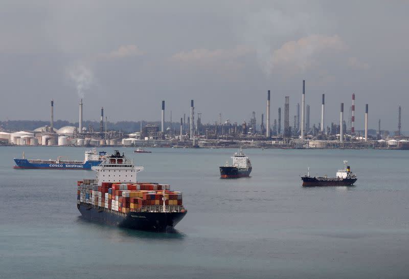 FILE PHOTO: A container ship passes Shell's Pulau Bukom refinery in Singapore