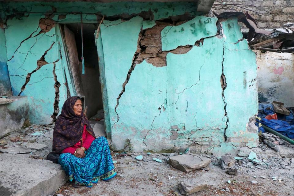 A woman sits beside a cracked wall of her house at Joshimath (AFP/Getty)