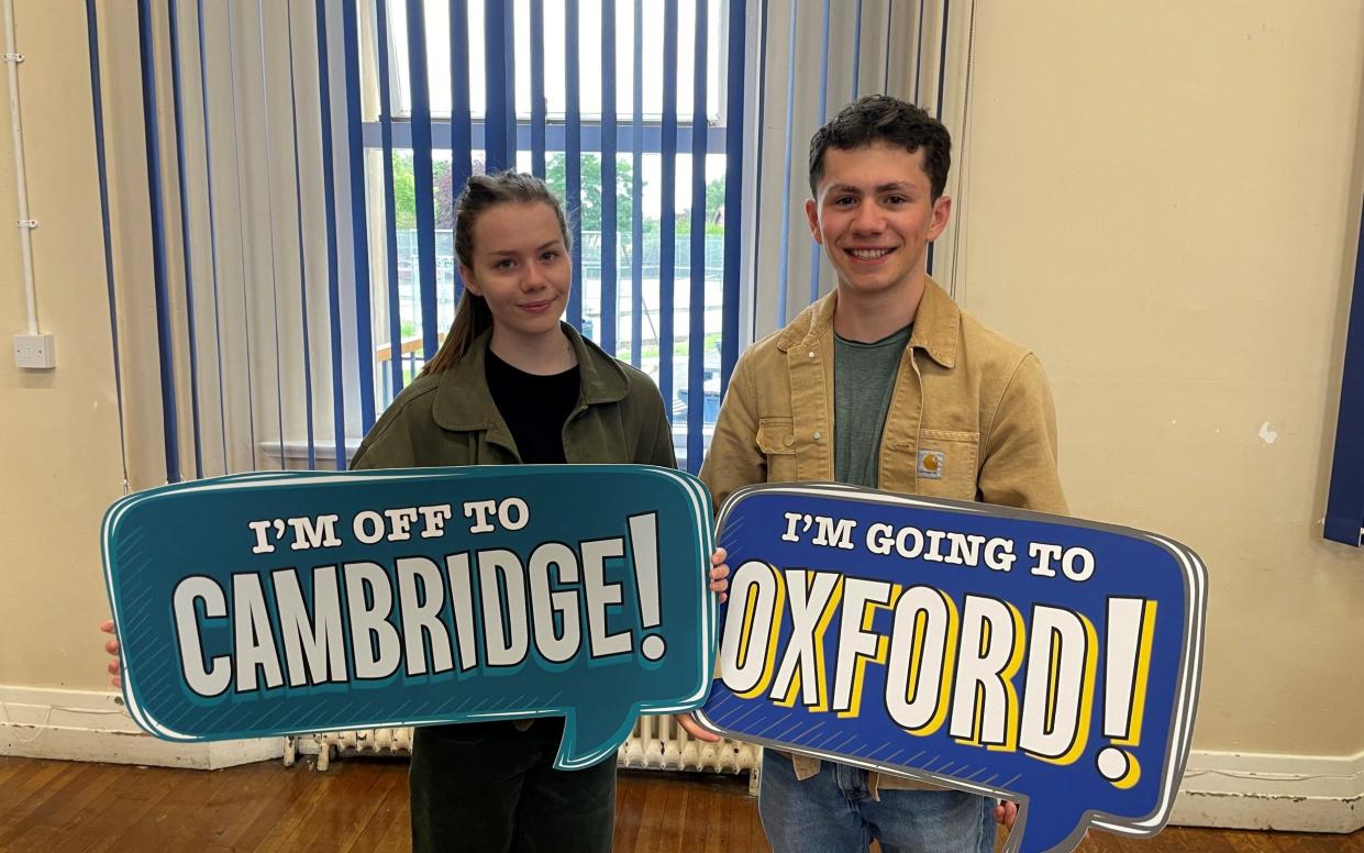 Twins Martha and Reuben Meadows hold up signs saying 'I'm off to Cambridge!' and 'I'm off to Oxford!' - York Press/SWNS