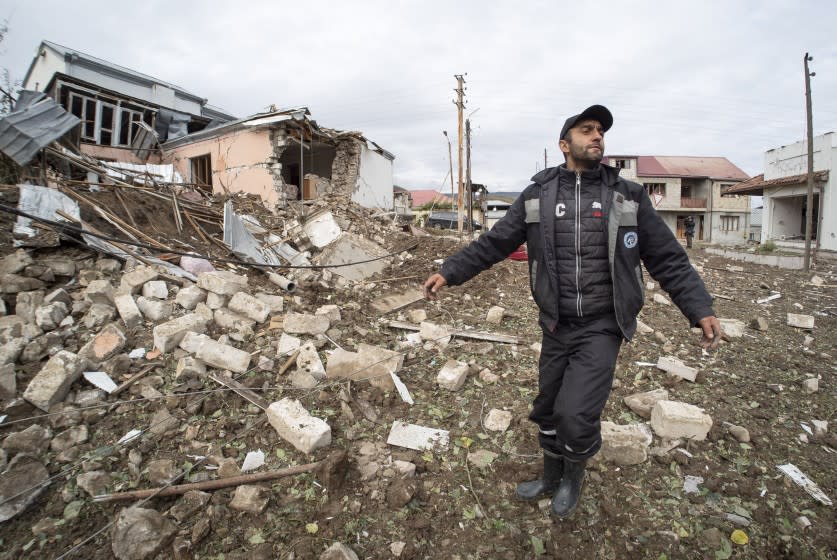 A man gestures near a house destroyed by shelling by Azerbaijan's artillery during a military conflict in Stepanakert, self-proclaimed Republic of Nagorno-Karabakh, Thursday, Oct. 8, 2020. Armenia accused Azerbaijan of firing missiles into the capital of the separatist territory of Nagorno-Karabakh, while Azerbaijan said several of its towns and its second-largest city were attacked. (AP Photo)