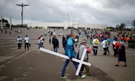 On the day before the arrival of Pope Francis, a pilgrim carries a cross at the Catholic shrine of Fatima, Portugal May 11, 2017. REUTERS/Rafael Marchante