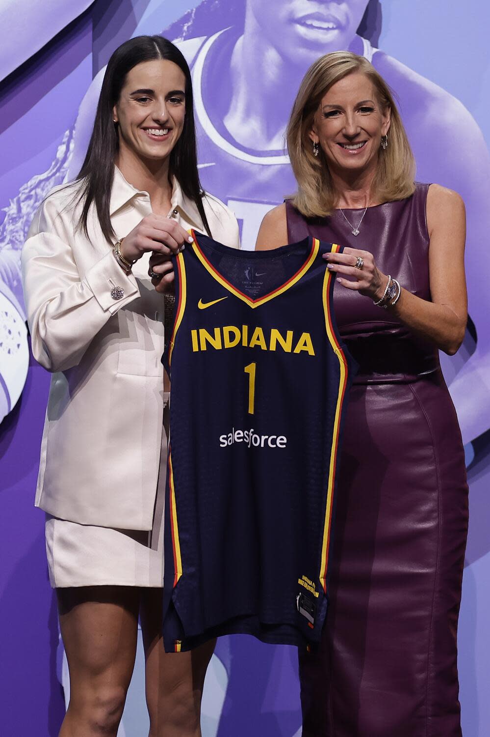 Caitlin Clark and WNBA commissioner Cathy Engelbert hold up an Indiana Fever jersey onstage at the WNBA draft.